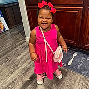 Bella joined the competition — help win amazing prizes! child, smiling, pink_dress, hair_bows, shoes, purse, indoor, floor, kitchen, cabinet, wood_floor, happy, toddler, standing, person, cute, fashion, accessory, expression, young_child