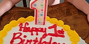 Liam is registered to the contest to win money with this photo: baby, birthday_cake, cake, celebration, child, colorful, curious, dessert, face, food, happy, home, icing, indoors, number_candle, one_year_old, party, person, table, wooden_chair