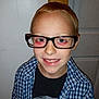 child, boy, glasses, smile, red_hair, blue_checkered_shirt, black_tshirt, indoor, door, wall, portrait, happy, casual_clothing, light_skin, standing, young, person, eyewear, closeup, front_view