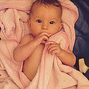 Inaya participe au concours pour gagner de l'argent avec cette photo : baby, blanket, child, cozy, cute, eyes, face, hand, hooded_towel, indoors, infant, lying_down, person, pink, portrait, skin, soft_texture, towel, wrapped, young