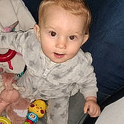 Inaya participe au concours pour gagner de l'argent avec cette photo : baby, child, colorful, couch, cute, face, hair_tie, hand, indoor, infant, pajamas, person, play_area, plush, red_eye, sitting, smile, soft_toys, toys, young_child