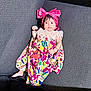 Nyra Adithi Darshan is registered to the contest to win money with this photo: baby, infant, child, dress, headband, pink_bow, bracelet, couch, sofa, fabric, colorful, pattern, textile, indoor, person, portrait, relaxing, lying_down, cute, young