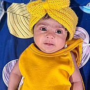 Nyra Adithi Darshan is registered to the contest to win money with this photo: baby, infant, yellow_headband, yellow_clothing, knitted_bow, blue_blanket, patterned_blanket, child, portrait, face, eyes, cute, smiling, lying_down, indoors, closeup, skin, headwear, expression, sleepwear