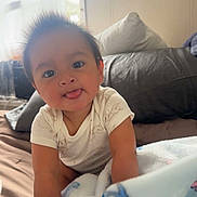 Thiago is registered to the contest to win money with this photo: baby, child, tongue_out, hair, blanket, bed, pillow, indoor, window, soft_light, cute, smiling, infant, white_clothing, crawling, face, person, cozy, home, young