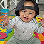 baby, child, smiling, cap, colorful, foam_mat, indoor, toy, sitting, happy, cute, clothing, sock, playful, young_child, home, floor, person, expression, fun