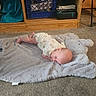 Chelsea is registered to the contest to win money with this photo: baby, infant, child, lying_down, blanket, stuffed_animal, bunny, carpet, living_room, shelf, furniture, home, portrait, face, smiling, eyes_open, onesie, indoors, crawling, cozy