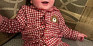 Ellis is registered to the contest to win money with this photo: baby, checkered, child, clothing, couch, curious, face, happy, head, indoor, infant, pajamas, patterned, person, red, seated, smiling, sofa, white, young
