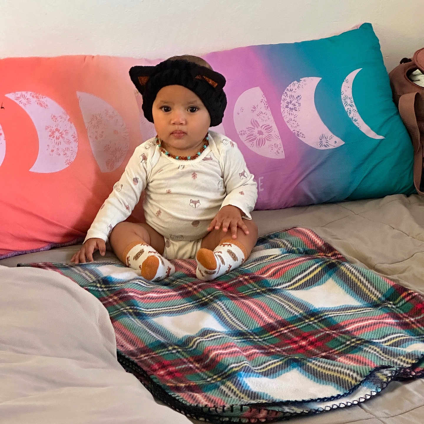 Vapalfi is registered to the contest to win money with this photo: baby, bed, blanket, cat_ears, child, clothing, cute, decor, hat, headwear, home, indoor, infant, moon_phases, person, pillow, plaid_blanket, portrait, seated, socks