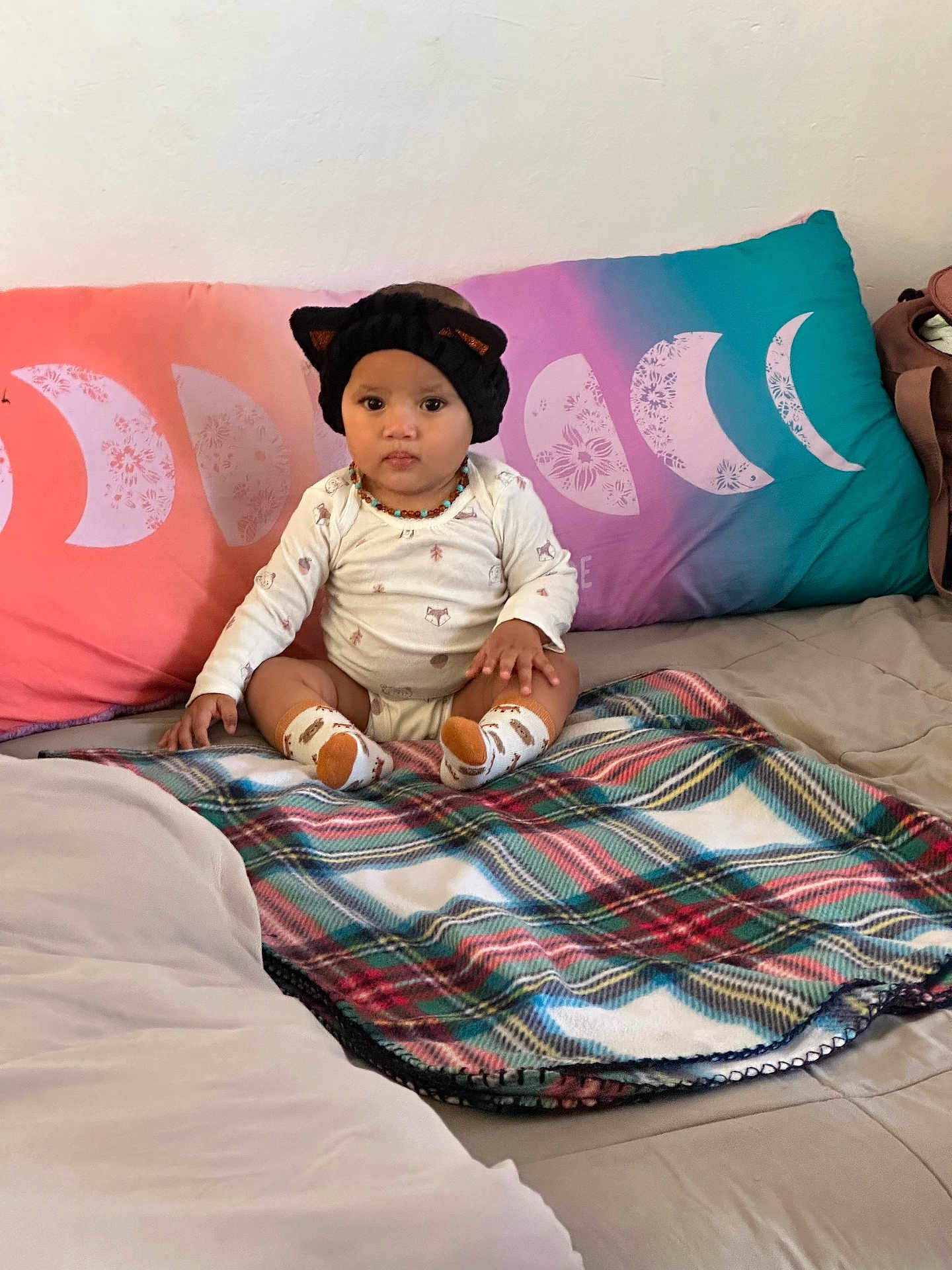 Vapalfi is registered to the contest to win money with this photo: baby, child, hat, cat_ears, socks, plaid_blanket, bed, pillow, moon_phases, indoor, clothing, person, cute, portrait, seated, blanket, headwear, infant, home, decor