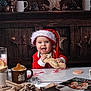 Eléa participe au concours pour gagner de l'argent avec cette photo : baby, child, santa_hat, red_clothing, gingerbread_plush, pinecones, candy_cane, cookie_cutter, mug, holiday_decor, christmas_book, wooden_background, table, smiling, festive, indoors, cute, toy, christmas_theme, happy
