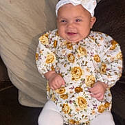 Maelani is registered to the contest to win money with this photo: baby, child, comfort, couch, cute, fashion, floral_outfit, happy, headband, headwear, indoor, infant, person, pillows, portrait, seated, smiling, soft_furniture, toddler, white_tights
