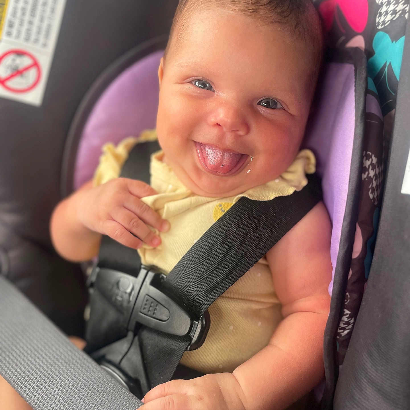 Maelani is registered to the contest to win money with this photo: baby, child, car_seat, smiling, tongue_out, happy, infant, seatbelt, safety, cute, portrait, closeup, clothing, yellow, hand, face, seat, colorful, funny, cheerful