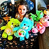 child, girl, toddler, smiling, portrait, indoors, couch, stuffed_animals, teddy_bears, plush_toys, superhero, costume, colorful, toys, seated, curly_hair, happy, living_room, furniture, family_photo