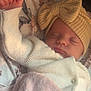baby, infant, newborn, sleeping, hat, knit_hat, bow, blanket, swaddle, cozy, peaceful, portrait, close_up, hand, fist, pink_blanket, white_cardigan, button, floral_bedding, sleepy_face