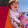 toddler, child, smiling, toy, pink_toy, colorful, playtime, happy, cute, indoors, sitting, clothing, cardigan, patterned_pants, barefoot, sunlight, flooring, playmat, person, portrait