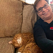 Jemmy is registered to the contest to win money with this photo: woman, cat, orange_cat, white_patches, sleeping, smiling, glasses, portrait, selfie, couch, sofa, cushion, indoors, home, relaxed, cozy, sweater, rose, long_hair, pet