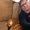 woman, cat, orange_cat, white_patches, sleeping, smiling, glasses, portrait, selfie, couch, sofa, cushion, indoors, home, relaxed, cozy, sweater, rose, long_hair, pet