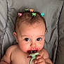 baby, cheeks, child, colorful, cute, expression, eyes, hair_clips, hand, high_chair, indoor, infant, juice, messy_face, person, portrait, seat, skin, teething_ring, young