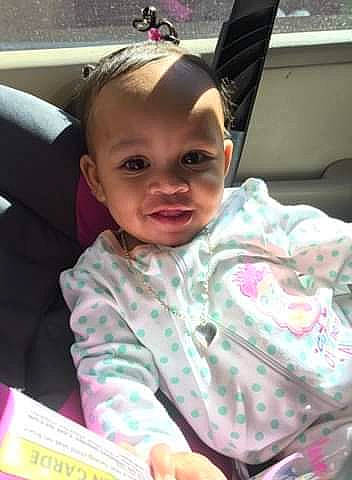 Maiya is registered to the contest to win money with this photo: baby, black_hair, car_seat, cheek, child, daughter, ear, eyebrow, face, forehead, hair, hair_accessory, hairstyle, head, lip, nose, person, pink, skin, smile