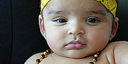 Pahal joined the competition — help win amazing prizes! baby, child, face, headband, peacock_feather, necklace, yellow_clothing, bare_chest, infant, portrait, cute, indoor, sitting, closeup, expression, skin, jewelry, person, young, adorable