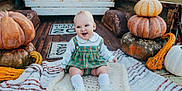 Brent is registered to the contest to win money with this photo: baby, bread, clothing, face, food, footwear, happy, head, laughing, person, photography, plant, portrait, produce, pumpkin, shoe, sitting, smile, squash, vegetable
