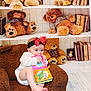 Raylynn is registered to the contest to win money with this photo: baby, child, red_bow, headband, book, sea_turtle, teddy_bear, stuffed_animal, chair, brown, bookshelf, books, indoor, floor, wooden_floor, cute, infant, reading, playful, cozy
