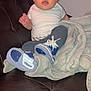 Rayanna is registered to the contest to win money with this photo: baby, child, infant, couch, blanket, clothing, sneakers, white_shirt, gray_pants, curly_hair, indoor, person, seated, looking_at_camera, cozy, leather_couch, footwear, casual, young_child, portrait