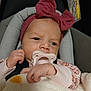 baby, infant, pacifier, headband, bow, blanket, car_seat, safety, warning_label, clothing, pink, cute, child, newborn, face, hand, portrait, indoors, soft, cozy