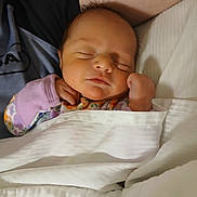 Makenna Layne is registered to the contest to win money with this photo: baby, sleeping, newborn, blanket, bed, pillow, person, hand, face, cozy, infant, rest, peaceful, soft, clothing, lying_down, portrait, cute, indoors, closeup