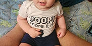 Kenneth joined the competition — help win amazing prizes! toddler, child, baby, person, sitting, legs, shirt, text, blue_eyes, blanket, dinosaur_pattern, clothing, indoor, cute, face, smile, shorts, skin, hair, home