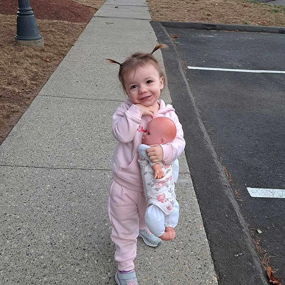 Sadie is registered to the contest to win money with this photo: baby, ball, city, clothing, coat, face, football, head, pants, path, person, photography, portrait, road, sidewalk, soccer, soccerball, street, urban, walking