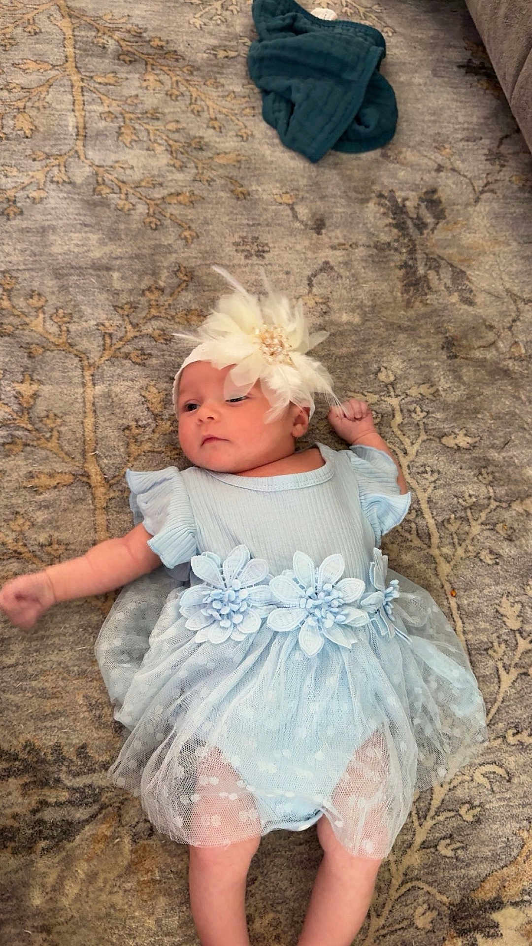 Vanessa joined the competition — help win amazing prizes! baby, infant, blue_dress, flower_headband, carpet, pattern, cute, lying_down, child, soft_fabric, indoors, peaceful, small_hands, small_feet, adorable, portrait, floor, delicate, resting, curious