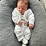Reginald is registered to the contest to win money with this photo: baby, newborn, sleeping, white_clothing, knitted_sweater, gray_cushion, soft_texture, cozy, infant, cute, resting, indoors, portrait, peaceful, small_hands, closed_eyes, baby_socks, comfort, relaxation, child