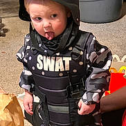 Brayden joined the competition — help win amazing prizes! toddler, child, costume, swat, helmet, playful, tongue_out, indoors, carpet, camouflage, vest, toy_walkie_talkie, person, cute, funny_face, small_child, sitting, floor, home, pretend_play