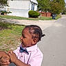 adult_hand, bow_tie, boy, child, dandelions, daylight, grass, house, outdoor, pink_shirt, polka_dots, portrait, short_hair, side_profile, smiling, street, suburban, toddler, trees, walking