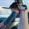 puppy, sleeping, hands, tattoo, car, window, vehicle, sky, peaceful, cute, small, animal, pet, human, arm, interior, closeup, resting, daylight, nature