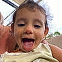 child, toddler, face, tongue_out, close_up, candid, curly_hair, messy_hair, necklace, tank_top, stain, outdoor, patio, canopy, sky, smiling, playful, portrait, cute, person