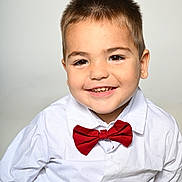 Lissandro a rejoint le concours — aidez-le/la à gagner de superbes lots ! child, boy, smile, portrait, red_bow_tie, white_shirt, short_hair, brown_eyes, teeth, cute, studio_background, sitting, denim_shorts, ear, eyebrows, formalwear, closeup, happy, skin, fashion