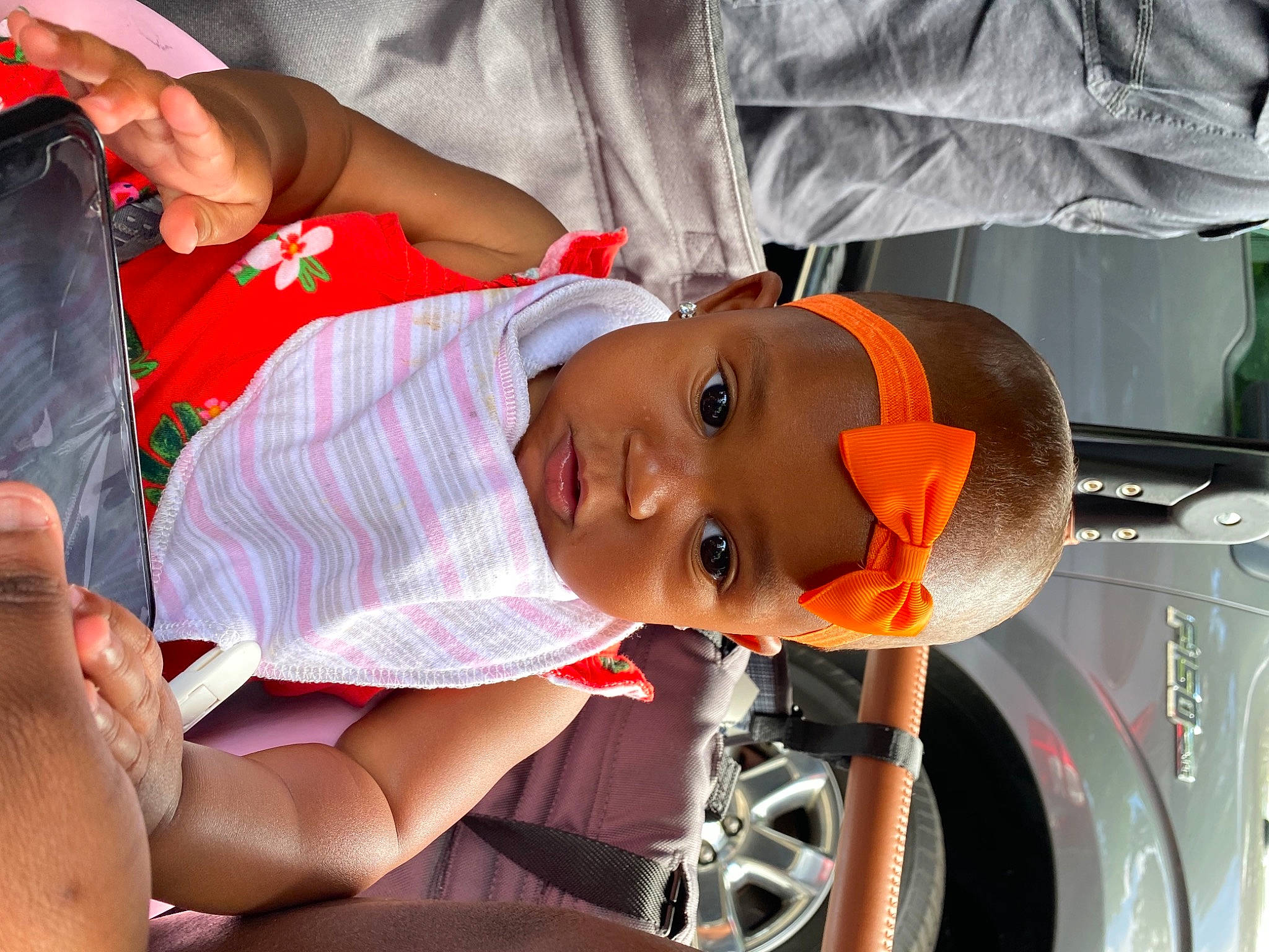 Kayla is registered to the contest to win money with this photo: automotive_design, automotive_lighting, automotive_tire, baby, baby_products, car_seat, chest, child, elbow, event, fun, hat, motor_vehicle, mouth, orange, person, product, sunglasses, thigh, toddler