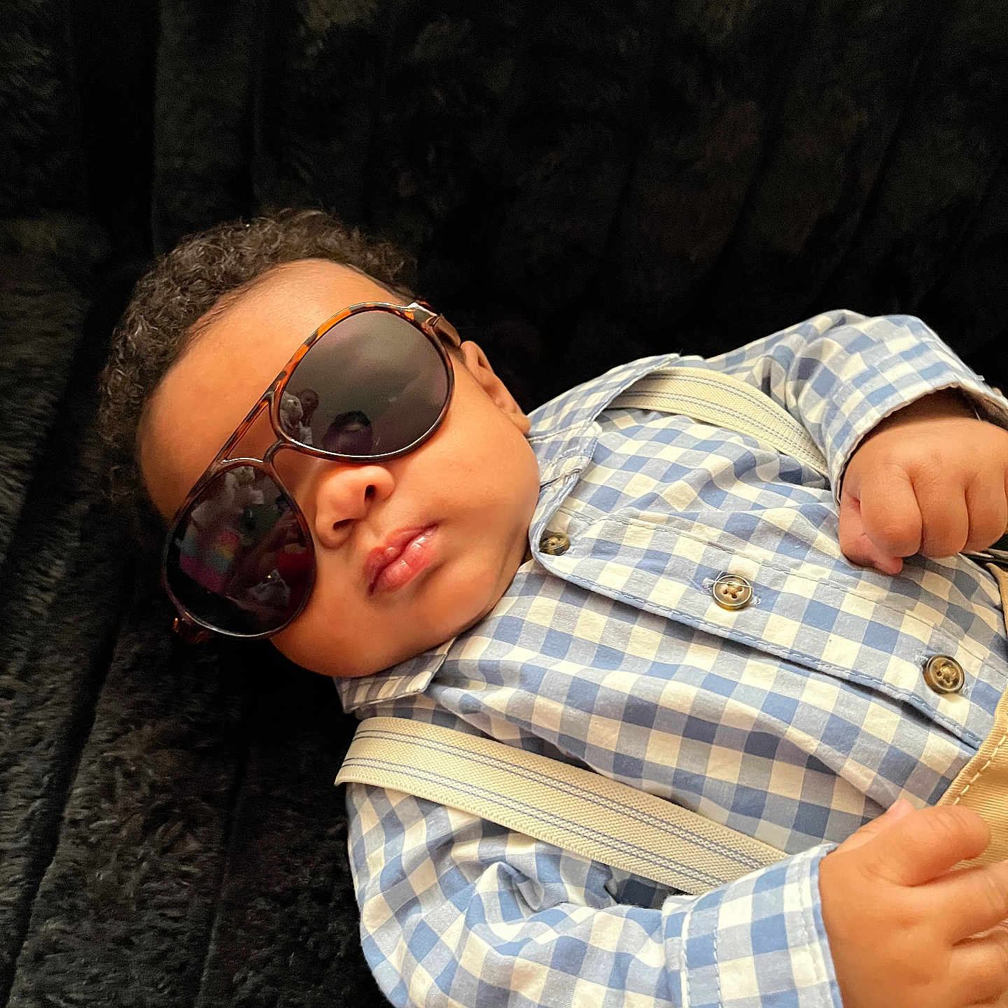 Jai Ceon is registered to the contest to win money with this photo: accessory, baby, blue_checkered_shirt, casual, child, closeup, cool, curly_hair, cute, fashion, indoor, infant, person, plush_surface, portrait, relaxed, resting, small_hands, sunglasses, suspenders