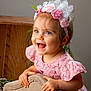 toddler, child, smiling, pink_dress, lace, headband, flowers, blue_eyes, happy, portrait, indoor, cushion, chair, wooden_background, greenery, cute, young_child, baby, hands, face