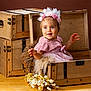 Alix a rejoint le concours — aidez-le/la à gagner de superbes lots ! baby, child, pink_dress, headband, flower_crown, wooden_chest, vintage_trunk, dried_flowers, table, portrait, smiling, happy, indoor, studio, cute, infant, decor, wood, rustic, background