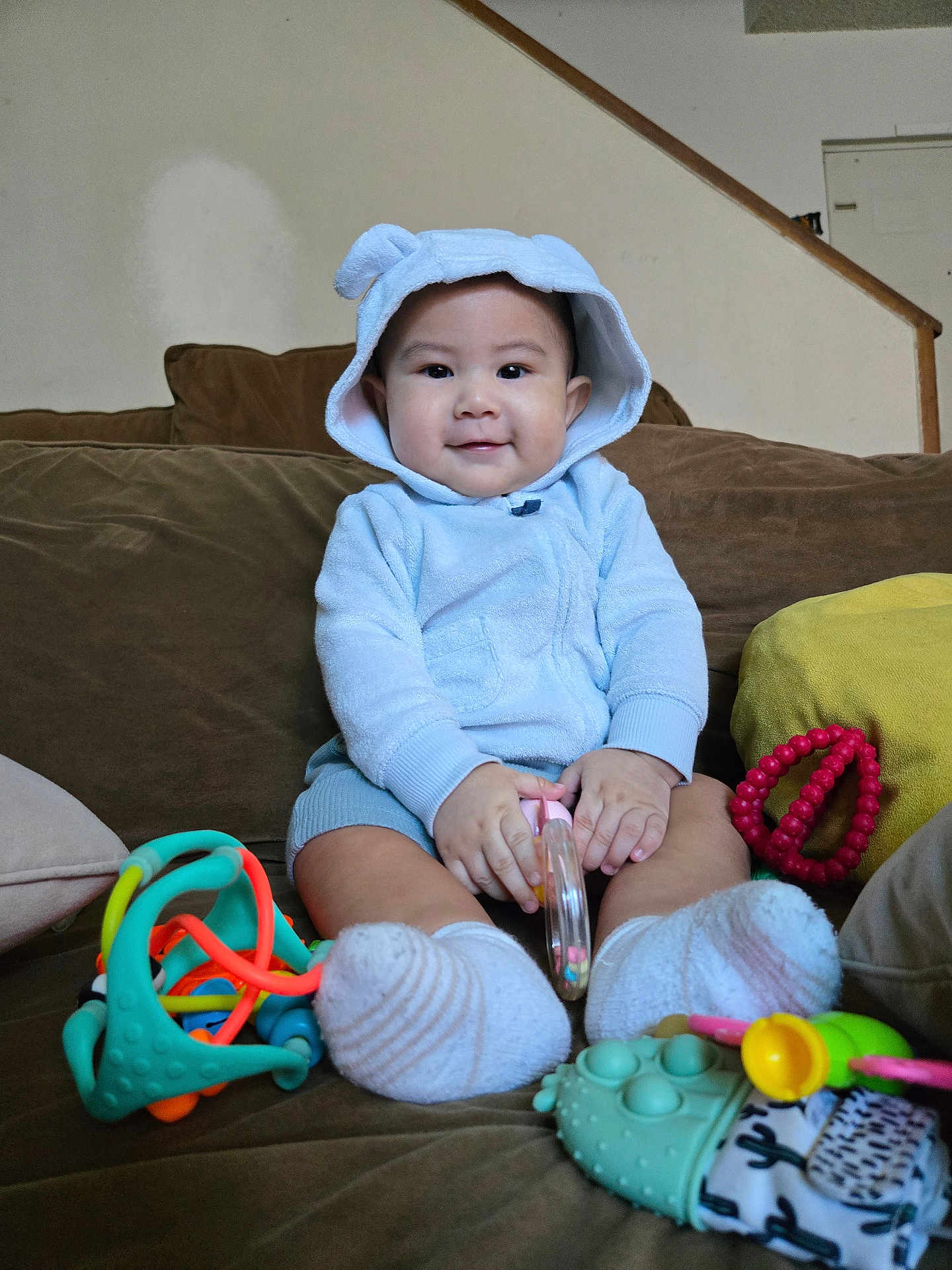 Michael joined the competition — help win amazing prizes! baby, child, hoodie, blue_clothing, smile, toy, couch, indoor, infant, cute, socks, playtime, happy, person, young_child, soft_toys, seated, home, comfort, casual