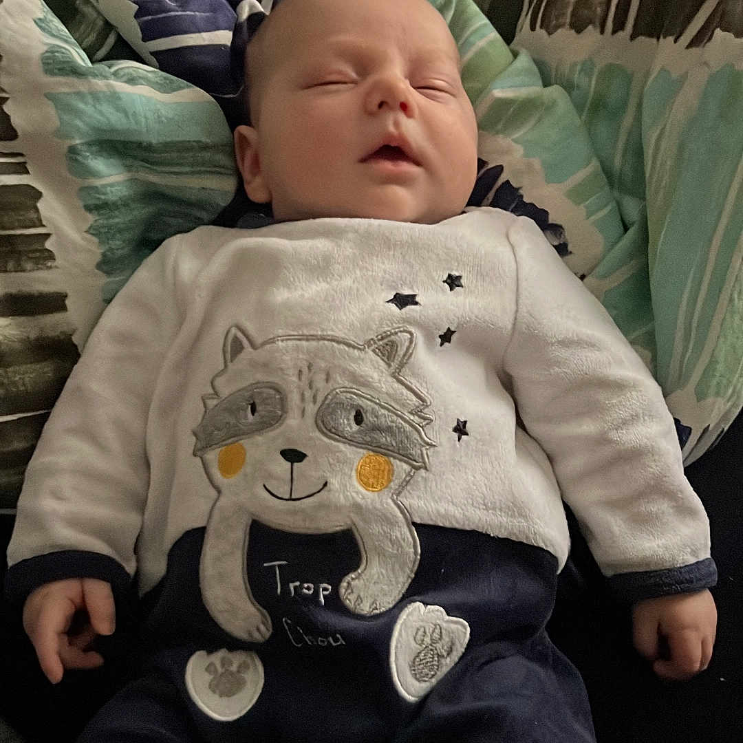 émyjio participe au concours pour gagner de l'argent avec cette photo : apparel, baby, blanket, child, clothing, comfort, cozy, cute, face, hands, indoors, infant, patterned, peaceful, person, resting, sleeping, soft, toddler, young