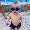 toddler, goggles, swim_trunks, pool, water, child, summer, toys, barefoot, concrete, hair_spike, swimming, play, outdoor, kids, fun, blue, water_droplets, person, daylight