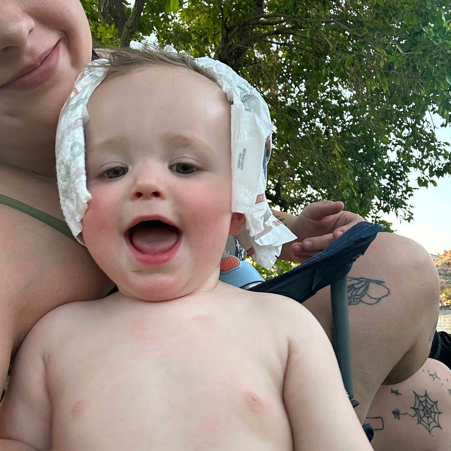 Ace is registered to the contest to win money with this photo: toddler, child, baby, smiling, happy, outdoor, nature, tree, adult, person, tattoo, skin, diaper, headwear, greenery, summer, joy, playful, closeup, family