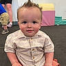 toddler, child, indoor, playroom, soft_play, colorful, spiky_hair, striped_shirt, orange_shorts, floor_mat, person, adult, legs, shoes, wall_art, sun_painting, casual_clothing, smiling, cute, sitting
