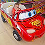 Solan a rejoint le concours — aidez-le/la à gagner de superbes lots ! amusement_park, cartoon, child, clothing, colorful, daytime, entertainment, family, fun, jacket, leisure, outdoor, person, playful, red_car, ride, serious_expression, toddler, toy_car, wheels