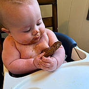 Jaxxon is registered to the contest to win money with this photo: baby, high_chair, cookie, food, messy, cereal, child, indoor, cute, curious, eating, face, hand, skin, table, seat, infant, expression, snack, meal