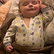 Angelito is registered to the contest to win money with this photo: baby, sleeping, onesie, paw_print, blanket, cozy, infant, hand, closed_eyes, smile, bedroom, pillow, soft_lighting, cute, child, indoor, peaceful, cute_outfit, sleep, toddler